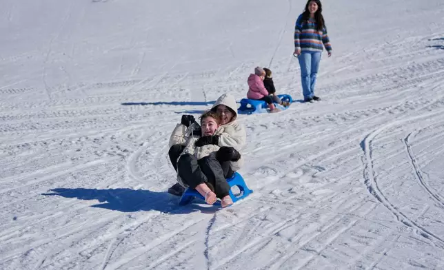 Families enjoy sledding in the snow at the Mzaar-Kfardebian ski resort northeast of Beirut, Lebanon, Saturday, Jan. 3, 2026. (AP Photo/Hassan Ammar)