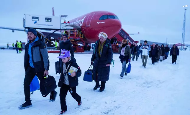 People walk out from a plane after arriving at the airport, in Nuuk, Greenland, on Monday, Jan. 12, 2026. (AP Photo/Evgeniy Maloletka)