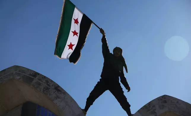 FILE - A soldier waves a Syrian flag amid celebrations a day after Syrian government troops took control of Raqqa from the Syrian Democratic Forces (SDF), at Al-Naeem roundabout in central Raqqa, northeastern Syria, Monday, Jan. 19, 2026. (AP Photo/Ghaith Alsayed, File)