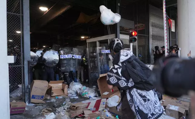Protesters throw trash at federal police blocking a loading dock at the Metropolitan Detention Center in downtown Los Angeles on Friday, Jan. 30,2026. (AP Photo/Jae C. Hong)