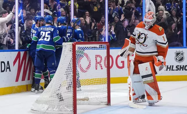 Vancouver Canucks' Drew O'Connor, back left to right, Elias Pettersson, Aatu Raty, Filip Hronek and Jake DeBrusk, hidden, back center, celebrate O'Connor's goal against Anaheim Ducks goalie Lukas Dostal (1) during the third period of an NHL hockey game, in Vancouver, on Thursday, Jan. 29, 2026. (Darryl Dyck/The Canadian Press via AP)