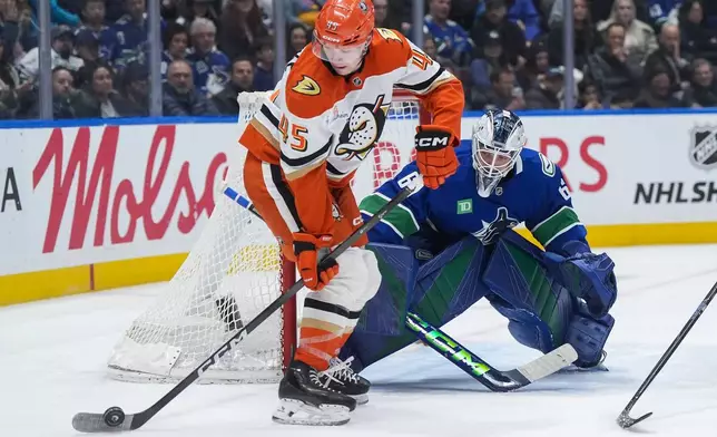 Vancouver Canucks goalie Nikita Tolopilo (60) watches as Anaheim Ducks' Beckett Sennecke (45) controls the puck in front of him during the second period of an NHL hockey game, in Vancouver, on Thursday, Jan. 29, 2026. (Darryl Dyck/The Canadian Press via AP)