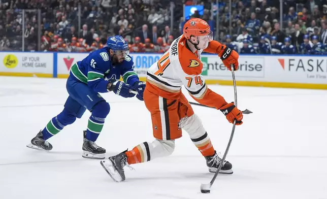 Anaheim Ducks' Ian Moore (74) takes a shot on goal while being checked by Vancouver Canucks' Evander Kane (91) during the first period of an NHL hockey game, in Vancouver, on Thursday, Jan. 29, 2026. (Darryl Dyck/The Canadian Press via AP)