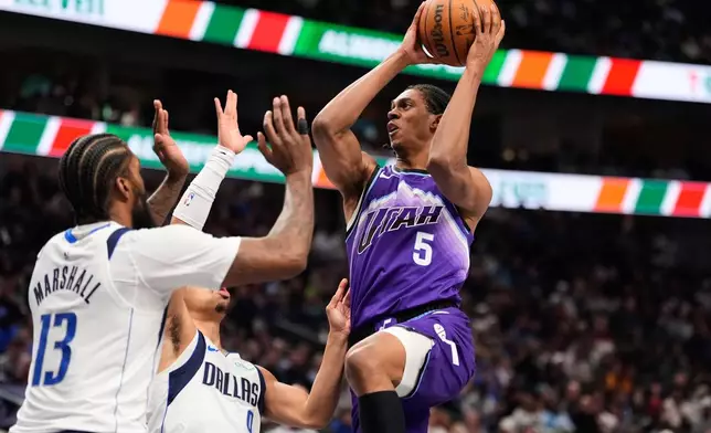 Utah Jazz forward Cody Williams (5) leaps to the basket to shoot as Dallas Mavericks' Naji Marshall (13) and Ryan Nembhard (9) defend in the first half of an NBA basketball game in Dallas, Saturday, Jan. 17, 2026. (AP Photo/Tony Gutierrez)
