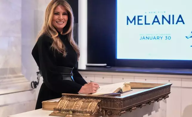 First lady Melania Trump signs the book on the floor of the New York Stock Exchange before ringing the opening bell, Wednesday, Jan. 28, 2026. (AP Photo/Richard Drew)