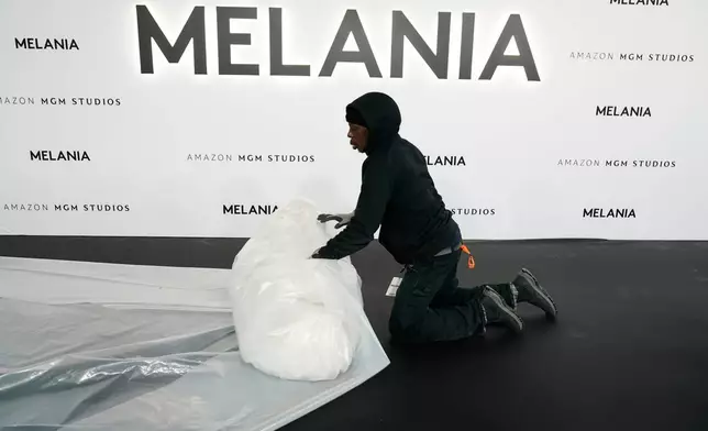 A worker removes plastic from the carpet before the premiere of first lady Melania Trump's movie "Melania" at The John F. Kennedy Memorial Center For The Performing Arts, Thursday, Jan. 29, 2026, in Washington. (AP Photo/Jose Luis Magana)