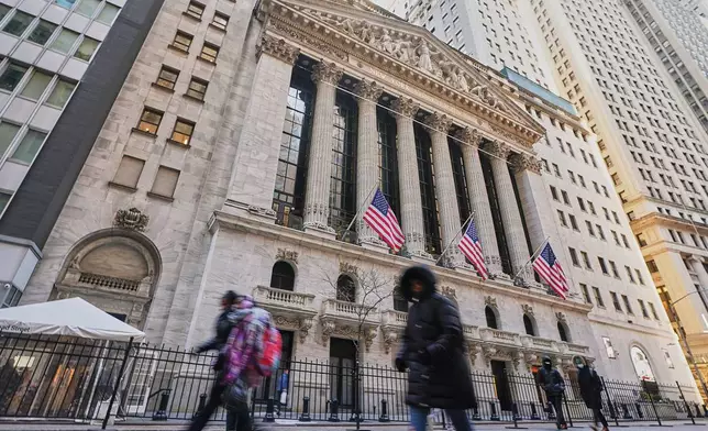 Morning commuters pass the New York Stock Exchange, Tuesday, Jan. 20, 2026. (AP Photo/Richard Drew)
