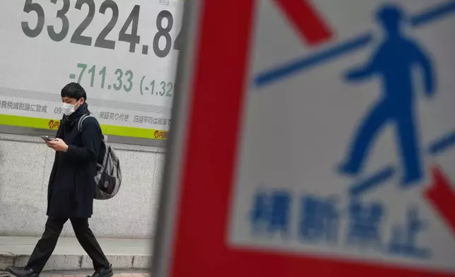 A person walks in front of an electronic stock board showing Japan's Nikkei index at a securities firm Monday, Jan. 19, 2026, in Tokyo. (AP Photo/Eugene Hoshiko)