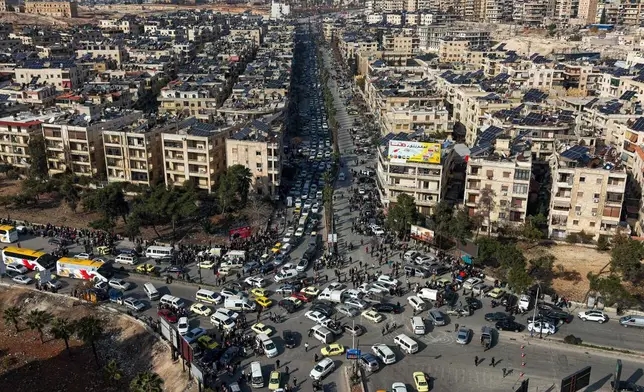 An aerial view shows Syrian residents in vehicles, queueing to flee from Sheikh Maqsoud and Achrafieh neighborhoods after clashes broke out on Tuesday between Syrian government forces and Kurdish fighters in a contested area of the northern city of Aleppo, Syria, Wednesday, Jan. 7, 2026. (AP Photo/Omar Albam)
