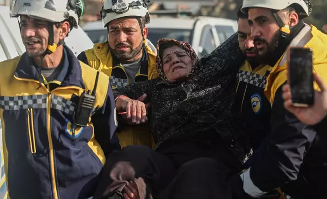 Members of the White Helmets, a volunteer civil defense group, help an elderly woman fleeing the Sheikh Maqsoud and Achrafieh neighborhoods in Aleppo, Syria, Thursday, Jan. 8, 2026, after clashes erupted Tuesday between Syrian government forces and Kurdish fighters. (AP Photo/Ghaith Alsayed)