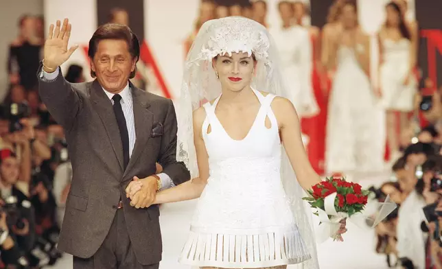 FILE - Italian fashion designer Valentino Garavani, left, waves to the public and holds by the hand American actress Sharon Stone wearing the wedding gown at the end of the presentation of Valentino's 1994 Spring/Summer ready-to-wear collection presented in Paris October 13, 1993. (AP Photo/Lionel Cironneau, File)