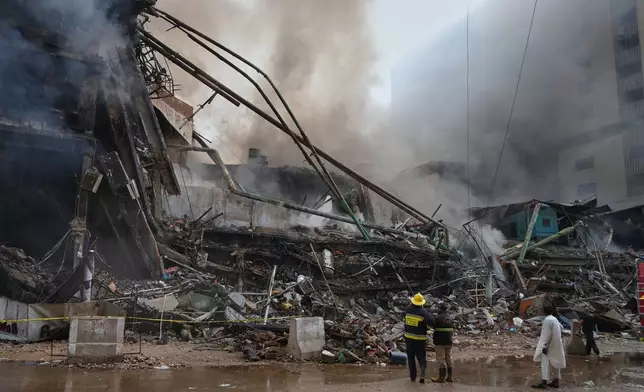 Firefighters examine a collapsed portion of a multi-story shopping mall following a massive fire that broke out overnight, in Karachi, Pakistan, Sunday, Jan. 18, 2026. (AP Photo/Mohammad Farooq)