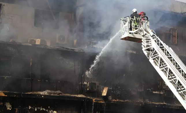 Firefighters pour water to control a massive fire that was broke out in a multi-story shopping mall overnight, in Karachi, Pakistan, Sunday, Jan. 18, 2026. (AP Photo/Mohammad Farooq)