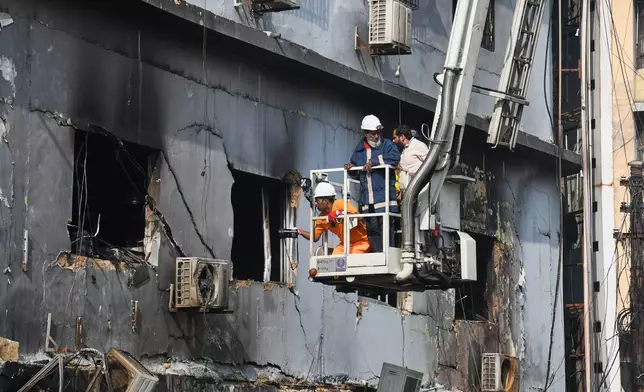 Firefighters search through the rubble of a burnt building of a multistory shopping plaza following a massive fire in Karachi, Pakistan, Monday, Jan. 19, 2026. (AP Photo/Ali Raza)
