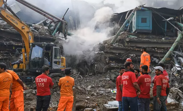 Rescue workers and firefighters work with heavy machinery to search through the rubble of a burnt building of a multistory shopping plaza following a massive fire in Karachi, Pakistan, Monday, Jan. 19, 2026. (AP Photo/Ali Raza)