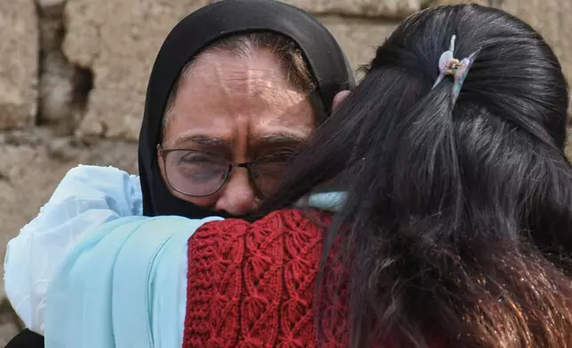 Family members of missing persons comfort each other as they wait near the site of a burnt building of a multistory shopping plaza following a massive fire in Karachi, Pakistan, Monday, Jan. 19, 2026. (AP Photo/Ali Raza)