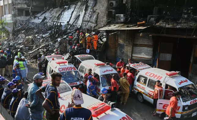 Ambulances are parked as rescue workers and firefighters work to search victims at the site of a burnt building of a multi-story shopping plaza following a massive fire in Karachi, Pakistan, Monday, Jan. 19, 2026. (AP Photo/Ali Raza)