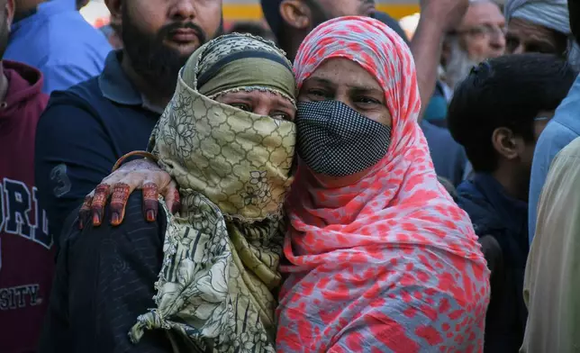 Family members of missing persons weep as they wait near the site of a burnt building of a multi-story shopping plaza following a massive fire in Karachi, Pakistan, Monday, Jan. 19, 2026. (AP Photo/Ali Raza)