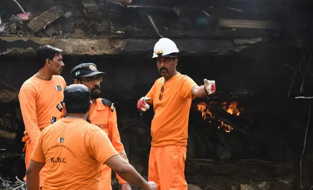 Firefighters search through the rubble of a burnt building of a multistory shopping plaza following a massive fire in Karachi, Pakistan, Monday, Jan. 19, 2026. (AP Photo/Ali Raza)