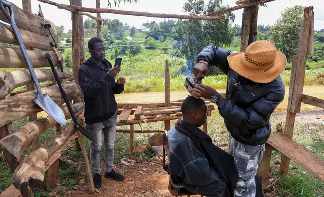 Barber and content creator Safari Martins uses a clothing iron as he shaves Ian Njenga in Kiambu, Kenya, Wednesday, Nov. 26, 2025. (AP Photo/Andrew Kasuku)