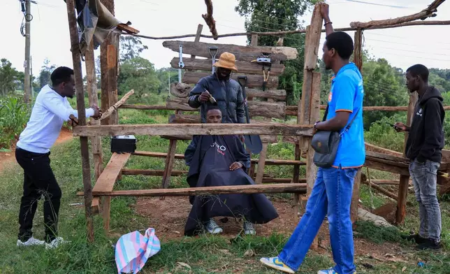 Barber and content creator Safari Martins shaves Ian Njenga in Kiambu, Kenya, Wednesday, Nov. 26, 2025. (AP Photo/Andrew Kasuku)