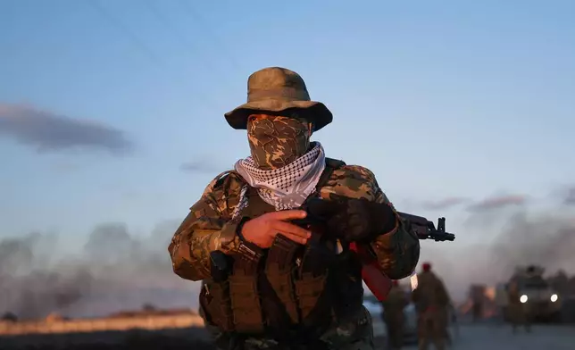 A Syrian government fighter stands guard outside Al-Aqtan prison on the outskirts of Raqqa, northeastern Syria, Monday, Jan. 19, 2026, as negotiations are underway with the Kurdish-led Syrian Democratic Forces over a withdrawal from the prison. (AP Photo/Ghaith Alsayed)