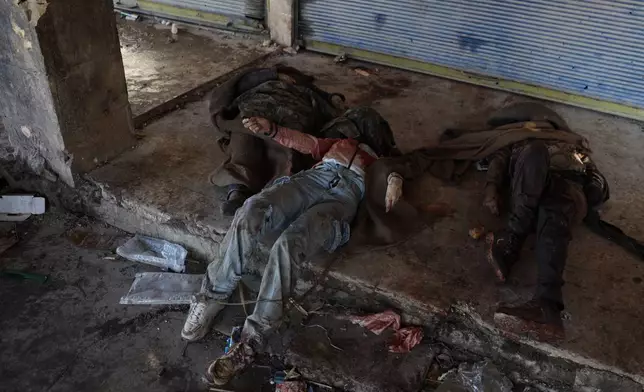 EDS NOTE: GRAPHIC CONTENT - Bodies of fighters with the Kurdish-led Syrian Democratic Forces lie on the ground near Al-Aqtan prison on the outskirts of Raqqa, northeastern Syria, Monday, Jan. 19, 2026, after fighting with Syrian government forces. (AP Photo/Omar Albam)