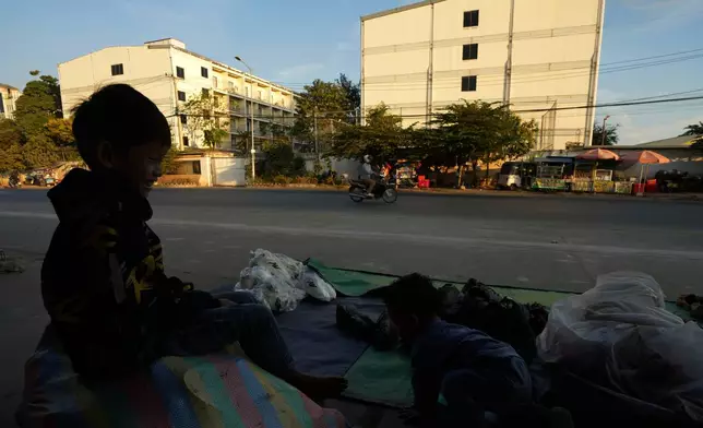 FILE - A boy plays near a building, where some people trafficked under false pretenses are being forced to work in online scams targeting people all over the world, in Phnom Penh, Cambodia, Feb. 9, 2025. (AP Photo/Heng Sinith, File)