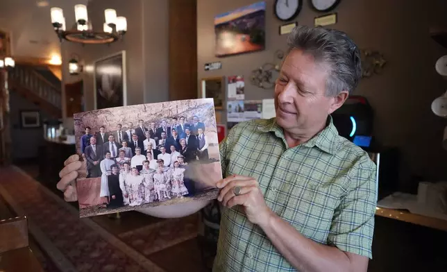 Shem Fischer, owner of the Zion Cliff Lodge, holds a photograph of the Fischer family reunion taken in 1995, during an interview Friday, Dec. 5, 2025, Hildale, Utah. (AP Photo/Rick Bowmer)