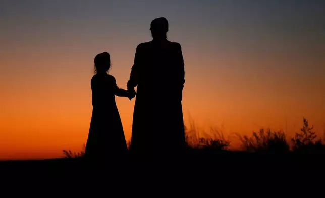 FILE - A woman and a young girl hold hands for a photograph, in Colorado City, Ariz., on Oct. 25, 2017. (AP Photo/Rick Bowmer, File)
