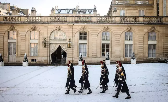 Republican Guards walk in the snow covered courtyard of the Elysee Palace in Paris, France, Tuesday, Jan. 6, 2026. (AP Photo/Thomas Padilla)