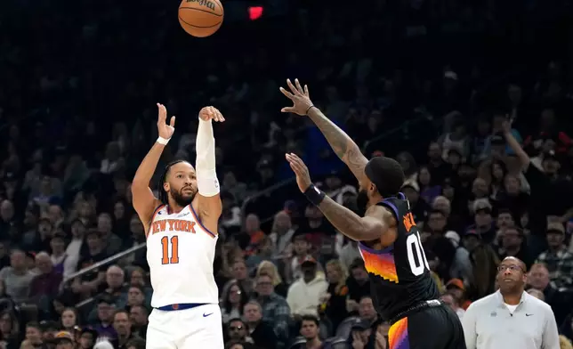 New York Knicks guard Jalen Brunson (11) shoots a 3-pointer over Phoenix Suns forward Royce O'Neale during the first half of an NBA basketball game, Friday, Jan. 9, 2026, in Phoenix. (AP Photo/Ross D. Franklin)