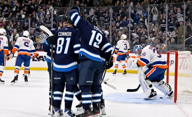 Winnipeg Jets' Jonathan Toews (19) celebrates his goal on New York Islanders goaltender Ilya Sorokin (30) with Kyle Connor (81) and teammates during the second period of their NHL hockey game, in Winnipeg, Manitoba, Tuesday Jan. 13, 2026. (Fred Greenslade/The Canadian Press via AP)