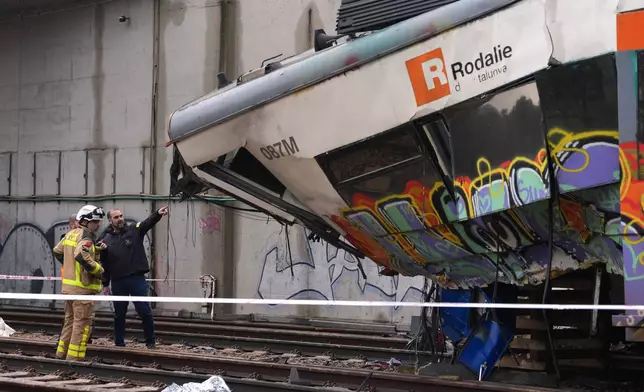 Police officers inspect the damage after a commuter train derailed as a retaining wall collapsed onto the tracks in Gelida, near Barcelona, Spain, Wednesday, Jan. 21, 2026. (AP Photo/Joan Mateu Parra)