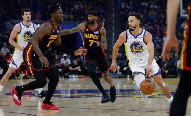 Golden State Warriors Stephen Curry (30) dribbles the ball past Atlanta Hawks Nickeil Alexander-Walker (7) during the first quarter of an NBA basketball game in San Francisco, Sunday, Jan. 11, 2026. (Carlos Avila Gonzalez/San Francisco Chronicle via AP)