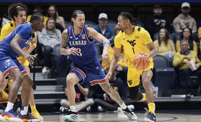 West Virginia guard Jasper Floyd (1) is defended by Kansas guard Tre White (3) during the second half of an NCAA college basketball game Saturday, Jan. 10, 2026, in Morgantown, W.Va. (AP Photo/Kathleen Batten)