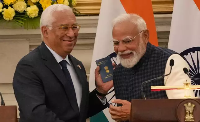 European Council President Antonio Costa, left, shows his Overseas Citizen of India (OCI) card to Indian Prime Minister Narendra Modi, during his press statement after reaching free trade agreement between India and EU in New Delhi, India, Tuesday, Jan. 27, 2026. (AP Photo/Manish Swarup)