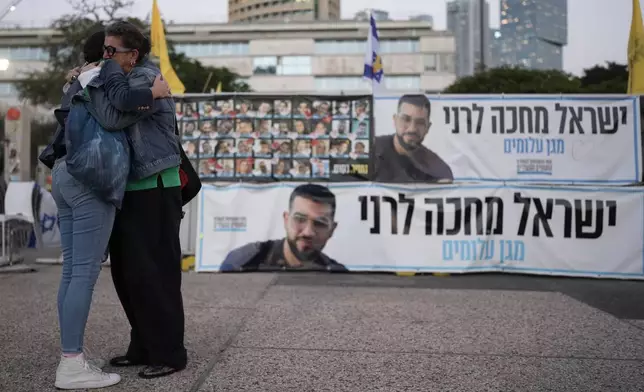 Two women embrace next to a banner with a photo of Ran Gvili after the announcement that the hostage, whose remains were the last to be recovered from Gaza, had been identified, in a plaza known as Hostages Square in Tel Aviv, Israel, Monday, Jan. 26, 2026. (AP Photo/Oded Balilty)