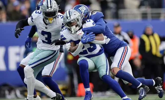 Dallas Cowboys running back Jaydon Blue (23) is tackled by New York Giants safety Dane Belton (24) during the first quarter of an NFL football game, Sunday, Jan. 4, 2026, in East Rutherford, N.J. (AP Photo/Adam Hunger)