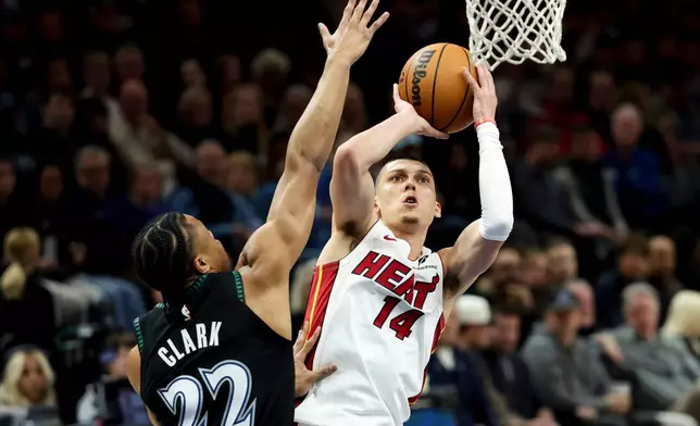 Miami Heat guard Tyler Herro (14) shoots against Minnesota Timberwolves guard Jaylen Clark (22) during the first half of an NBA basketball game, Tuesday, Jan. 6, 2026, in Minneapolis. (AP Photo/Ellen Schmidt)
