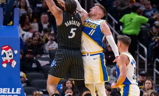 Orlando Magic forward Paolo Banchero (5) shoots while being defended by Indiana Pacers center James Wiseman (11) during the first half of an NBA basketball game in Indianapolis, Wednesday, Dec. 31, 2025. (AP Photo/Doug McSchooler)