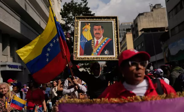 A government supporter holds an image of President Nicolas Maduro during a women's march to demand his return in Caracas, Venezuela, Tuesday, Jan. 6, 2026, three days after U.S. forces captured him and his wife. (AP Photo/Matias Delacroix)