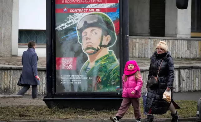 FILE - People walk past an army recruiting billboard with the words "Military service under contract in the armed forces," in St. Petersburg, Russia, March 24, 2023. (AP Photo, File)