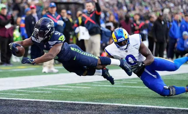 Seattle Seahawks running back Kenneth Walker III (9) scores a touchdown past Los Angeles Rams linebacker Byron Young (0) during the first half of the NFC Championship NFL football game Sunday, Jan. 25, 2026, in Seattle. (AP Photo/Stephen Brashear)