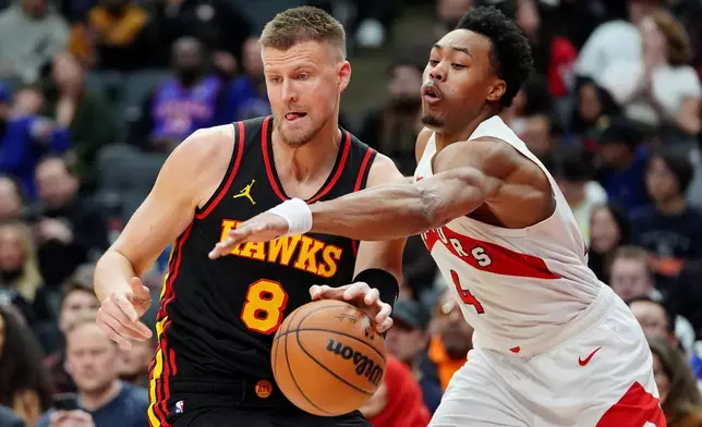 Toronto Raptors forward Scottie Barnes (4) tries to strip the ball from Atlanta Hawks centre Kristaps Porzingis (8) during second half NBA basketball action in Toronto, Monday, Jan. 5, 2026. (Frank Gunn/The Canadian Press via AP)