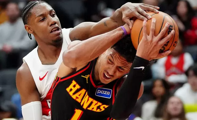 Toronto Raptors forward RJ Barrett, left, tries to strip the ball from Atlanta Hawks forward Jalen Johnson (1) during second-half NBA basketball game action in Toronto, Monday, Jan. 5, 2026. (Frank Gunn/The Canadian Press via AP)