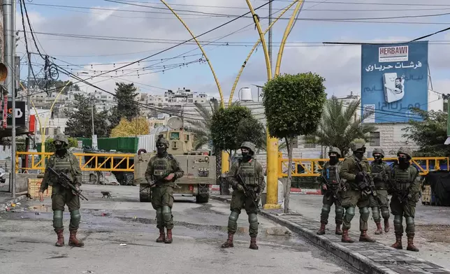 Israeli soldiers take up positions during an army raid in the West Bank city of Hebron Monday, Jan. 19, 2026. (AP Photo/Mahmoud Illean)