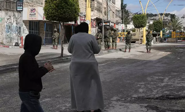 Israeli soldiers take up positions during an army raid in the West Bank city of Hebron Monday, Jan. 19, 2026. (AP Photo/Mahmoud Illean)