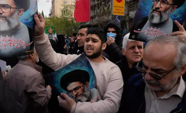 A man hands out posters of the Iranian Supreme Leader Ayatollah Ali Khamenei during a funeral ceremony for a group of security forces, who were killed during anti-government protests, in Tehran, Iran, Wednesday, Jan. 14, 2026. (AP Photo/Vahid Salemi)