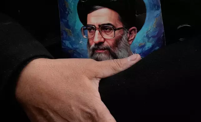 FILE - A man holds a poster of the Iranian Supreme Leader Ayatollah Ali Khamenei during a funeral ceremony for a group of security forces, who were killed during anti-government protests, in Tehran, Iran, Jan. 14, 2026. (AP Photo/Vahid Salemi, File)